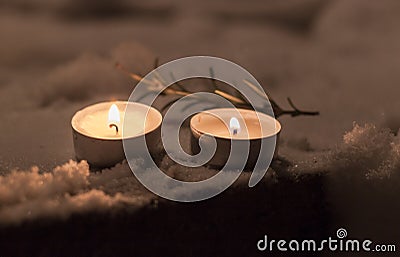 Candles with rosemary in the snow in yard Stock Photo