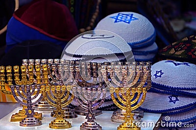 Candlesticks of the menorah are gold and silver. Knitted multi colored kipa are sold in the market in Jerusalem Stock Photo