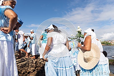 Candomble supporters walk on top of the rocks on Rio Vermelho beach to offer gifts to Yemanja Editorial Stock Photo