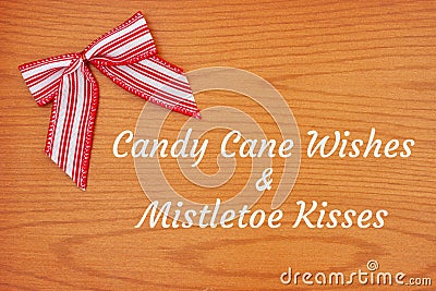 Candy cane wishes and mistletoe kisses greeting with Christmas red and white candy cane bow Stock Photo