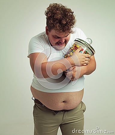 Candy, jar and man in studio for sweets, luxury snacks, and dessert in container. Comic, hungry and food, isolated and Stock Photo