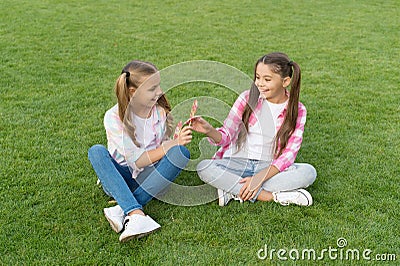 With candy you can put smile on friends face. Happy friends eat lollipops on green grass. Small friends enjoy summer Stock Photo