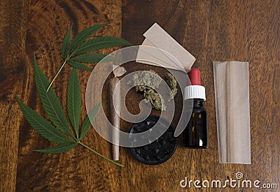 Cannabis sativa leafs and THC oil, with grinder and papers to smoke weed joint Stock Photo