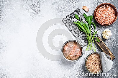 Canned tuna in a can, whole and chopped. Grey wooden background. Top view. Copy space Stock Photo