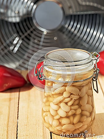 Canned white beans in a glass jar. On a wooden table are pockmarked with beans peppers and eggplant. Close-up Stock Photo