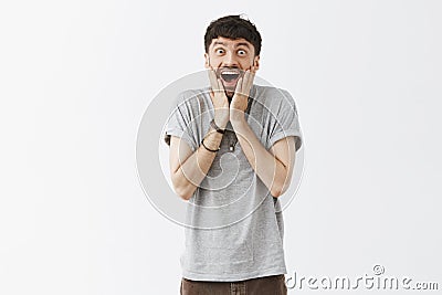 Cannot hide amazement inside, sharing great feelings. Portrait of good-looking amazed emotive black-haired guy with Stock Photo