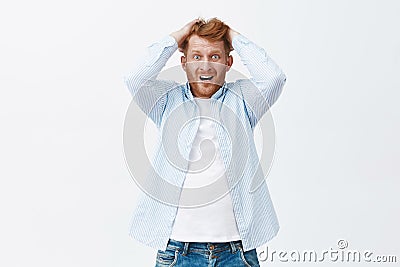 Cannot stop panicking. Portrait of anxious emotive european redhead man with bristle pulling hair out of head, gasping Stock Photo