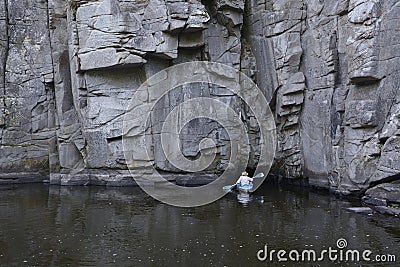 Canoe with people aboard going inside of a cave of rocks. Buksky canyon, Ukraine Stock Photo