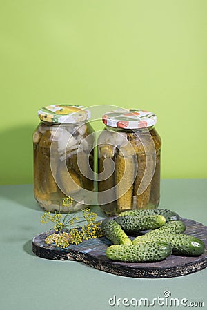 Cans of pickles and gherkins. Pickled pickles on a wooden chopping Board with herbs. Stock Photo