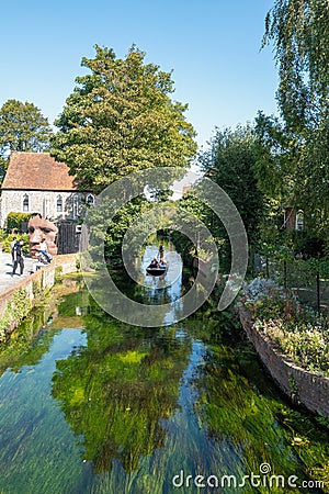 Canterbury, UK - Sep 27th 2020 Tourists enjoy a ride in a punt on the river Stour as it runs past the statue of the Bulkhead by Editorial Stock Photo