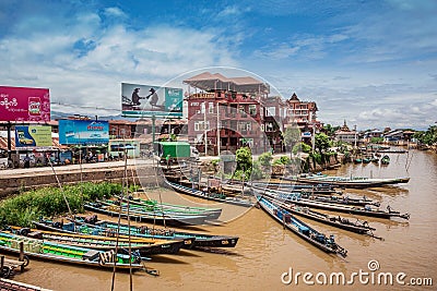 Inle Boat Station in Inle Nyaung Shwe Canal. A series of fishing boats along the river generated by Inle Lake. Homes in the backgr Editorial Stock Photo