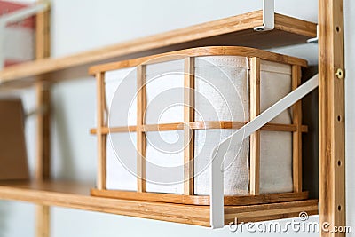 Canvas fabric storage basket with a wooden frame on the shelf. Eco-friendly design product for home decoration. Stock Photo