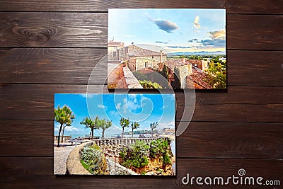 Canvas photo prints on brown wooden background. Front view of colorful photographs printed on glossy synthetic canvas. Photos Stock Photo