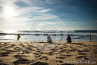 Capbreton, France - October 4, 2017: back view of women girls surfers sitting on sandy beach on surfboard Editorial Stock Photo