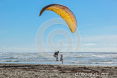 A skydiver landing on a beach of Oregon coast greeted by a random person Editorial Stock Photo