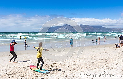 Surfing coach at Muizenberg beach teaching a young girl to surf at Surfers Corner Editorial Stock Photo