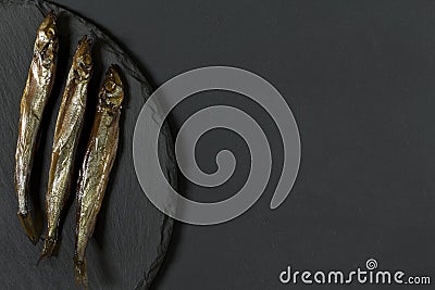 Capelin fish of cold smoked on round slate plate Stock Photo