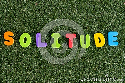 Capital letter `Solitude` word from colorful of wood on grass background. Stock Photo