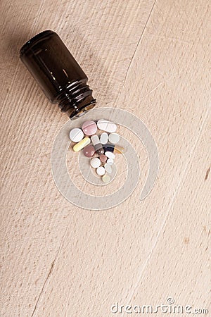 Caplets or pills in the opening of a medicine bottle on wooden board, view from above Stock Photo