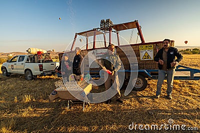Cappadocia, Turkey - September 14, 2021: Workers operating such as hot air balloon pilot opening champagne after safe landing to Editorial Stock Photo