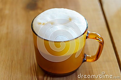 Cappuccino in a clear amber glass mug, with foam visible on top and layers visible through the glass Stock Photo