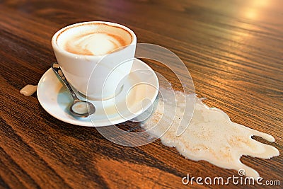 Cappuccino cup spilled. Coffee spill stain accident drop on desk Stock Photo