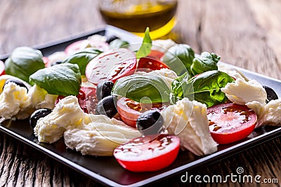 Caprese Salad.Mediterranean salad. Mozzarella cherry tomatoes basil and olive oil on old oak table. Italian cuisine Stock Photo