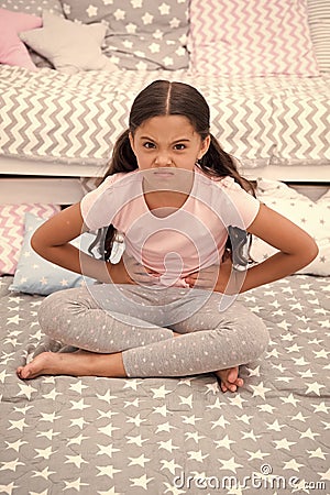 Capricious mood. Girl child sit in bedroom. Kid unhappy capricious someone entered her bedroom bothering . Girl kid long Stock Photo