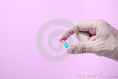 Capsule medicine in hand with pink background Stock Photo