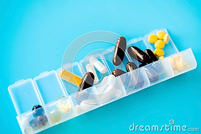 Capsules lie in a pill box on a blue background. Box for packing tablets for a week Stock Photo