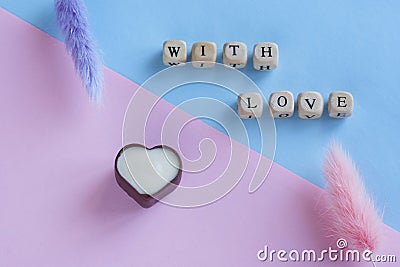 Caption with love next to flowers and heart shaped dark and white chocolate candy in dark and white chocolate. Pink and blue Stock Photo