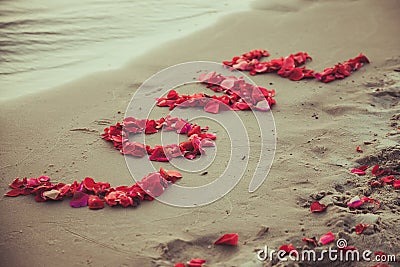 Caption word love in the sand of the sea. Love inscription from the petals of roses. Stock Photo