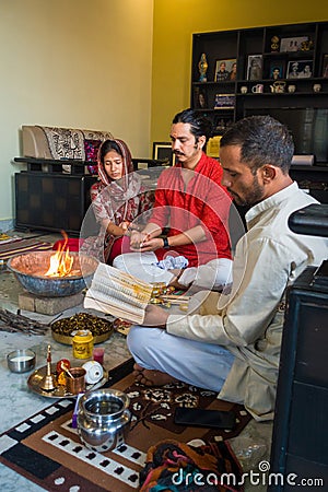 Captivating moment of Indian married couple participating in traditional Pooja and Hawan ceremony with a Pandit chanting mantras Editorial Stock Photo