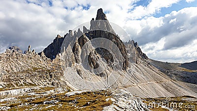 A capture of high and sharp peaks of Dolomites in Italy. Dried grass on the meadow. The sky is full of soft clouds. Stock Photo