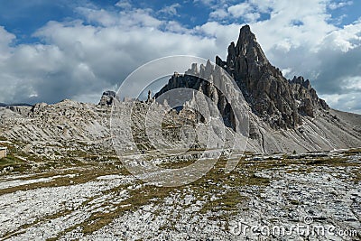 A capture of high and sharp peaks of Dolomites in Italy. Dried grass on the meadow. The sky is full of soft clouds Stock Photo