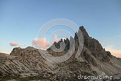 A capture of high and sharp peaks of Dolomites in Italy during the golden hour. The sky is full of soft clouds. Stock Photo