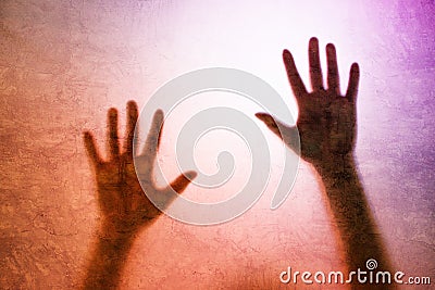 Captured person, back lit silhouette of hands behind matte glass Stock Photo