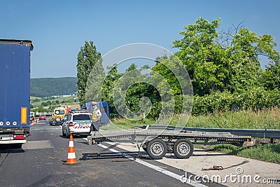 Car accident on highway. Overturned car after collision, ambulance, police car, policeman and deployed platform trailer Editorial Stock Photo