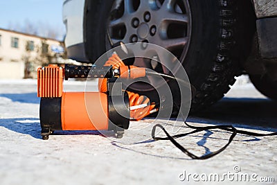 Car air compressor in working position at snow. Self-inflating wheels, automobile tire pressure control. Stock Photo