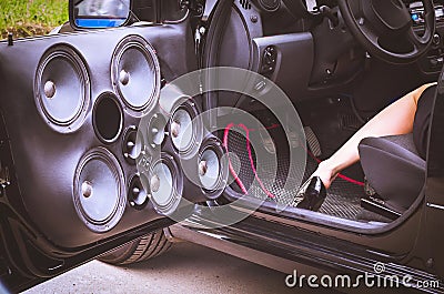 Car Audio System Speakers in the Opened Door with a Woman in High Heels Partially Visible Sitting in the Driverâ€™s Seat Stock Photo