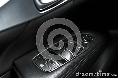 Car black perforated leather interior details of door handle with windows controls and adjustments. Car door handle inside the lux Stock Photo