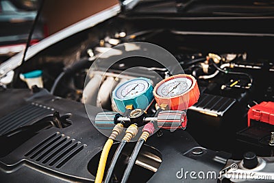 Car care maintenance and service, Hand technician auto mechanic using measuring manifold gauge check refrigerant and filling car Stock Photo