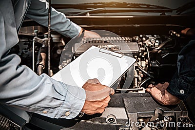 Hand mechanic using the checklist after change spare part car engine problem. Concepts of Stock Photo