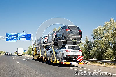 Car carrier trailer with new cars for sale on bunk platform. Car transport truck on the highway Stock Photo