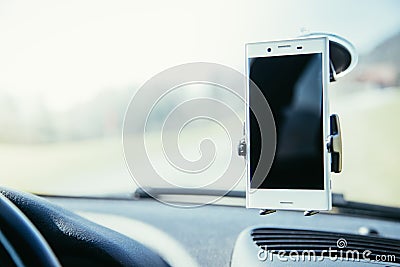 Car dashboard with smartphone used as navigation device, bright and sunny day Stock Photo