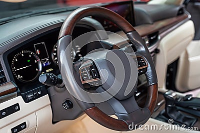 Car dashboard and steering wheel with media control buttons. Beige cockpit with exclusive wood decoration. Luxury Stock Photo