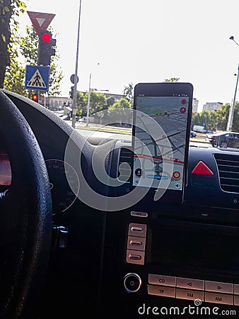 In car dashboard view with smartphone showing Waze maps to show the way thru the city. Driver using Waze maps in Bucharest, Editorial Stock Photo
