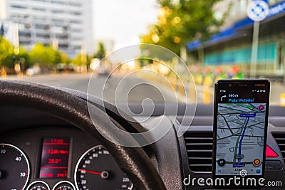 In car dashboard view with smartphone showing Waze maps to show the way thru the city. Driver using Waze maps in Bucharest, Editorial Stock Photo