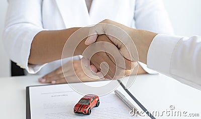 Car dealers or insurance dealers shake hands to congratulate the customers who have signed the car purchase contract with insuranc Stock Photo