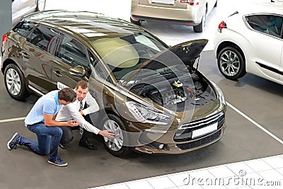 Car dealership advice - sellers and customers when buying a car - technology talk about the tires Stock Photo